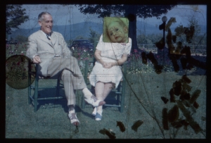 A film still of 2 elderly white people sitting on chairs on the grass. There are appliques and an image over the woman's face