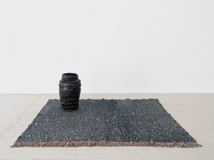 A black sculpture on a black and white jacquard rug
