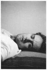 A black and white portrait of Guibert laying on a bed