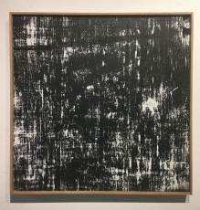 An abstract work of striations with black and white, in a wood frame