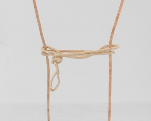 A plywood sculpture that is meant to look like a single carved line. The line describes a silhouette of a rectangle, which seems to have a rope strung and tied around the center.