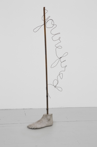 A sculpture of a concrete foot and a rebar pole sprouting from it. In wire, the words "You're fired" are written hanging off the side