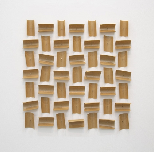 An arrangement of brown paper tape pieces pinned to the wall, 49 total