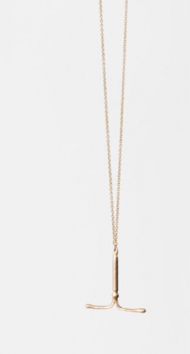 An image of an IUD made of brass, strung on a gold chain 
