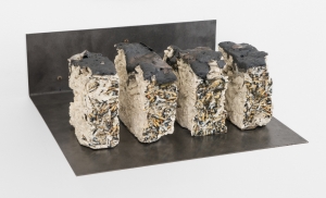 A mixed media clay sculpture with decals of cigarettes upon them