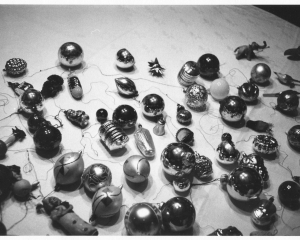 A black and white photograph of christmas ornaments, laid out upon a surface.