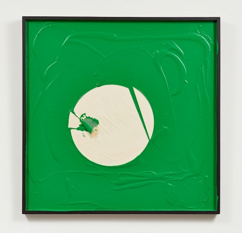 A predominantly green artwork in a white square frame. There are drips and pools of paint. In the middle is a circular shape made of paper, cut in several places but still generally in a circular shape.