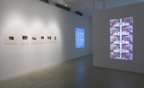 Two videos by Luther price, one on the foreground projected onto a temporary wall and the other is on the wall at left in the gallery. Additionally, the wall at left has 6 black and white photographs by Hervé Guibert in cream mattes.