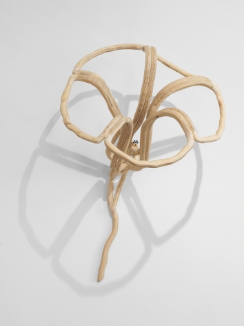 A sculpture of a flower silhouette hung on a wall, made of wood spindrels