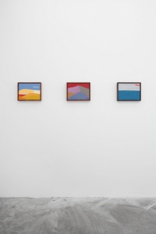 A photograph of 3 technicolor abstract landscapes hung on the wall