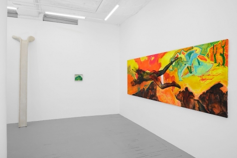 A photograph of the back quadrant of the gallery. There is a large, horizontal, brightly colored painting at right, taking up almost the entire wall. On the left there's a sculpture that leans on the wall, and a small painting to the right of it that is mostly green.