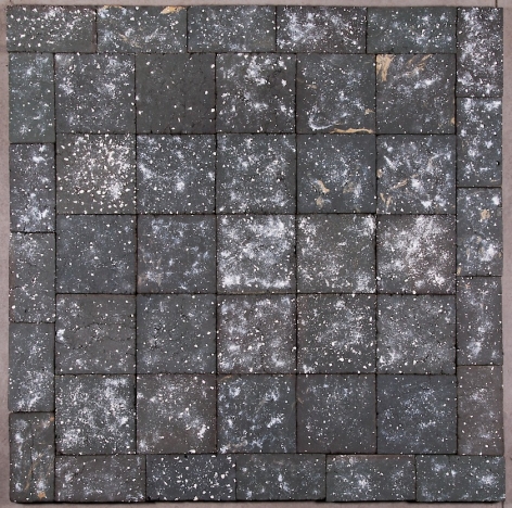 A square sculpture made up of 45 black clay tiles, here seen from above, with specks of white clay scattered throughout.