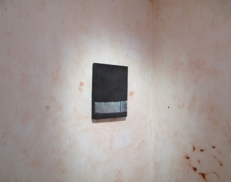 A photograph of one black and gray painting on a wall painted over with splotchy pink