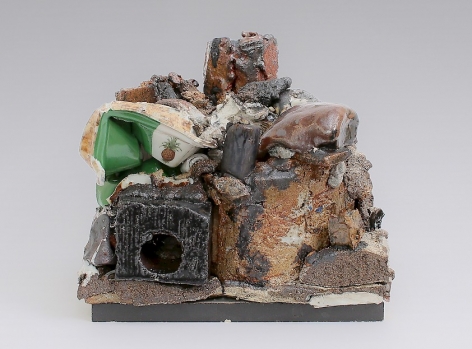 A mixed stoneware sculpture that includes highly textured surfaces in orange and beige. At left is a black square of stone in glossy enamel, and above it a trompe l'oeil styrofoam clamshell (made in porcelain) with decals applied on the surface.