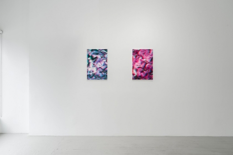 Two artworks installed on a white wall. One is blue-purple-white, the other is predominantly pink.