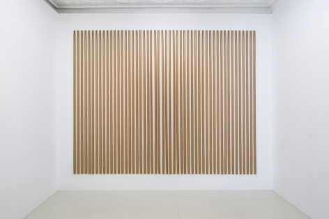 An installation of gummed paper tape, pinned at the top and bottom, in a rectangular arrangement of strips, taking up an entire wall
