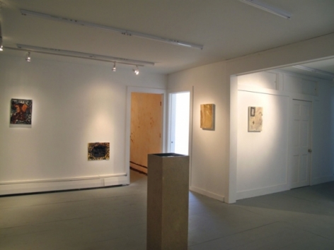 A photograph of 4 flat works on 3 walls. There is a pedestal in the middle of the room