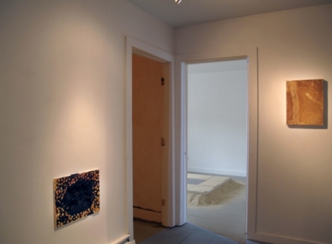 A photograph of 2 flat works on 2 walls. The doorway shows the site-specific tile work in the background