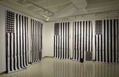 An installation of 5 black and white printed american flags