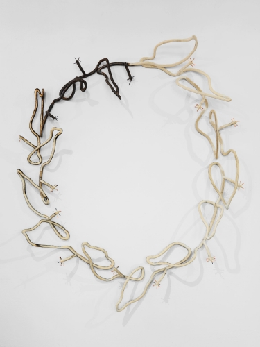 An image of a large wreath made of wood, with the upper-left burnt